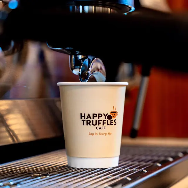 Fresh espresso in a Happy Truffles cup on the coffee machine